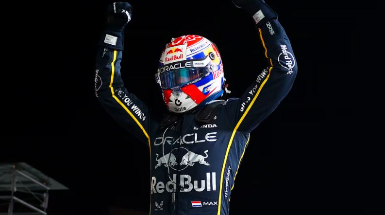 «مکس ورشتاپن راننده تیم ردبول ریسینگ در حال جشن گرفتن پیروزی در گرندپری فرمول یک لاسوگاس ۲۰۲۵، با پرچم تیم و نورهای درخشان خیابانهای لاسوگاس در پسزمینه»